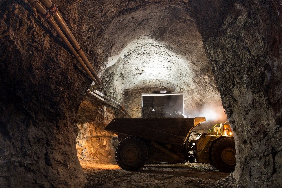 Un gros camion transportant des minéraux dans un tunnel sous terre.